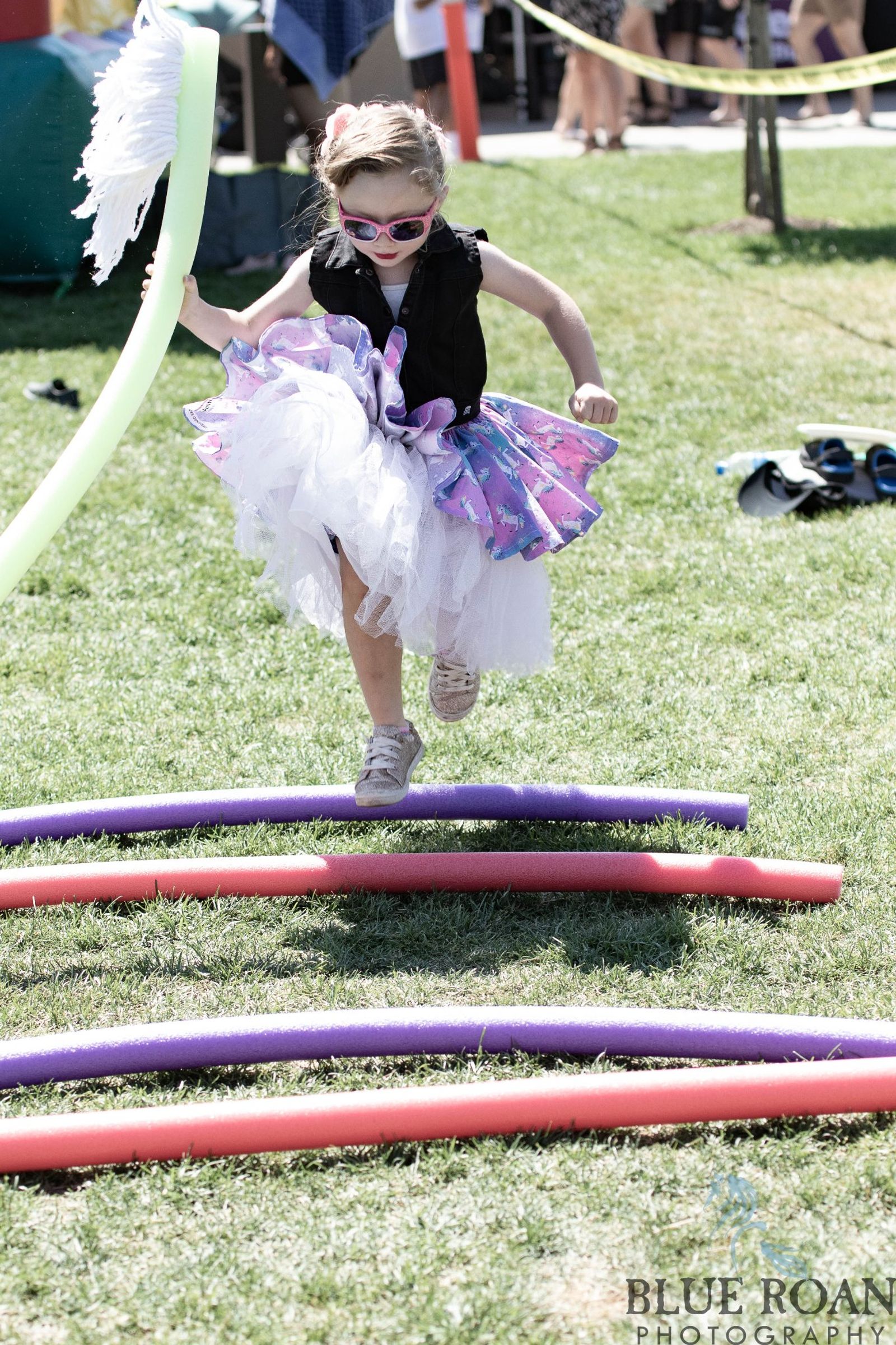 Young participant hopping through pool-noodle course in festive outfit