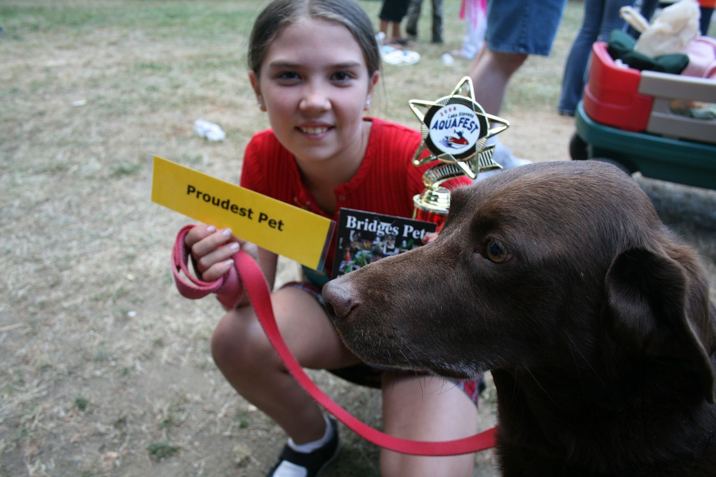 Young girl holding Proudest Pet award with her chocolate lab at Aquafest